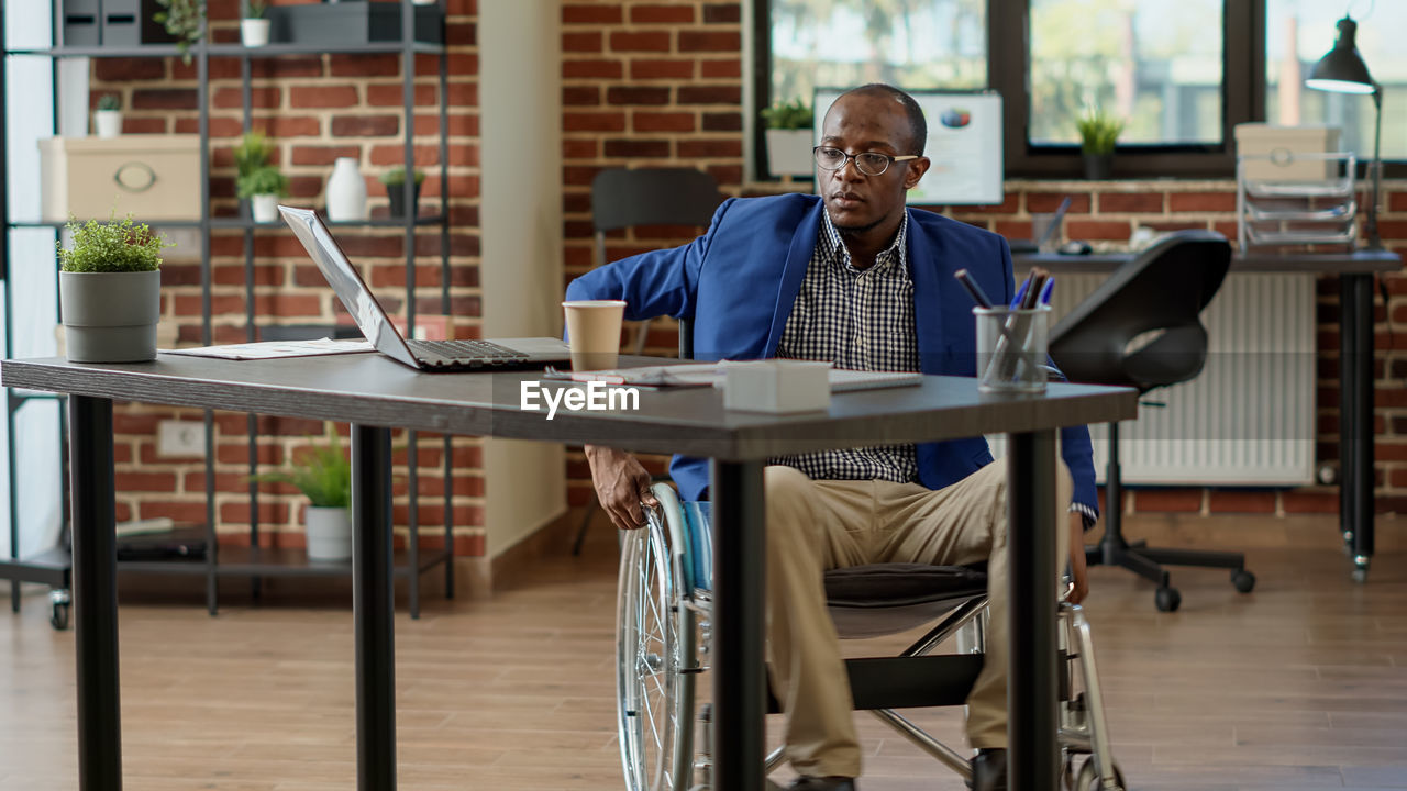 Businessman sitting on wheelchair in office