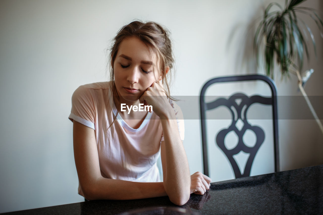 Young woman with eyes closed sitting at table