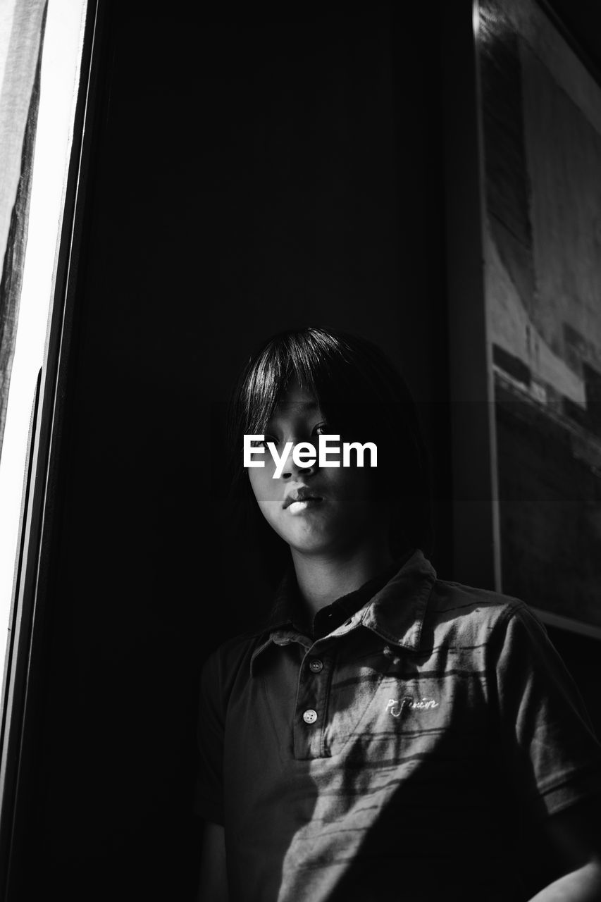 Low angle view of boy looking through window