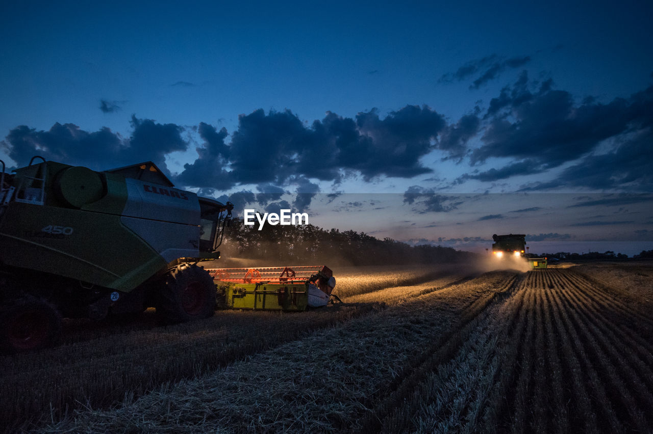 Illuminated machinery harvesting plants on field