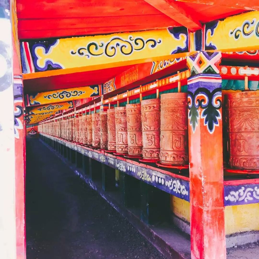 Row of prayer wheels outside temple