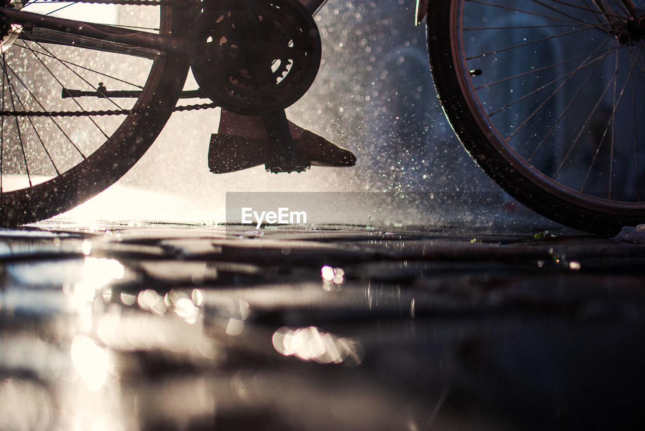 Low section of person cycling on wet footpath