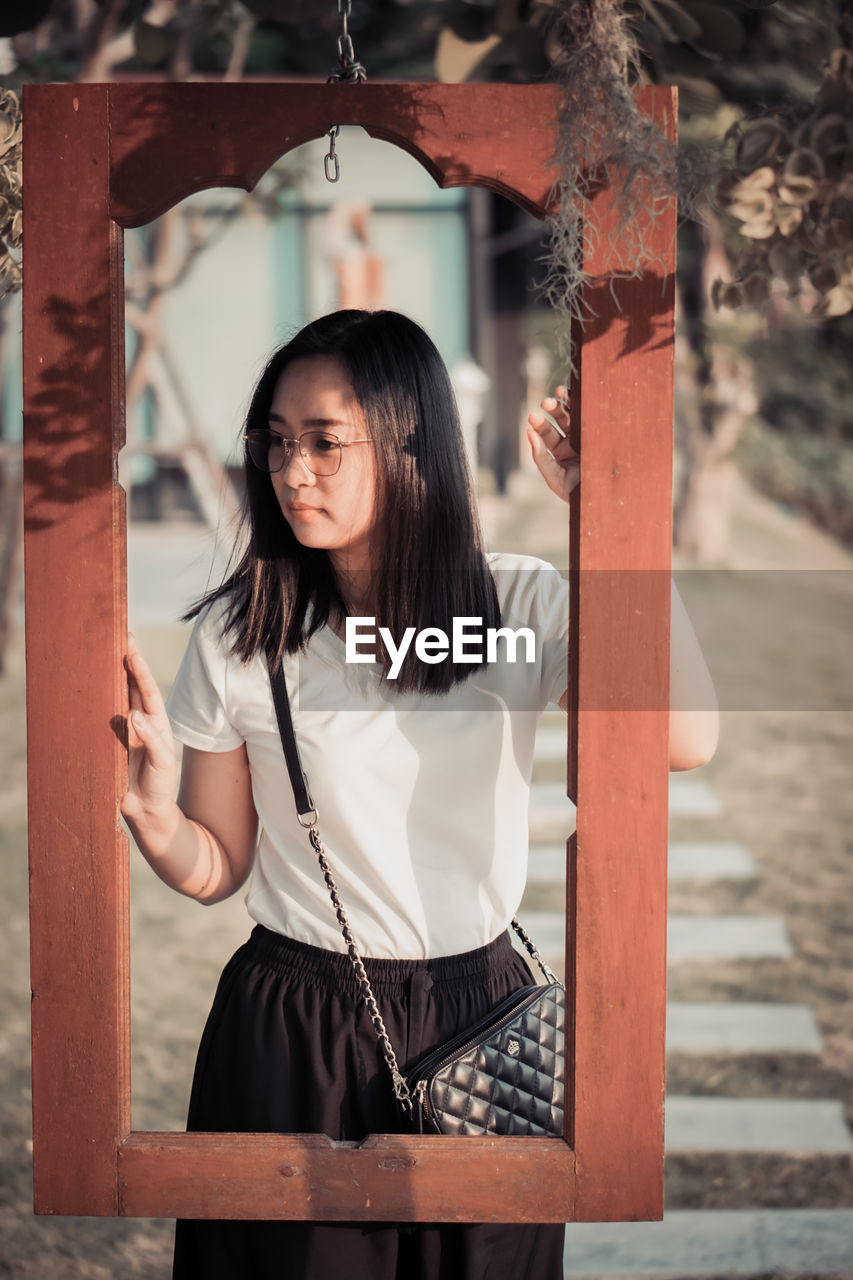 Portrait of young woman standing by railing