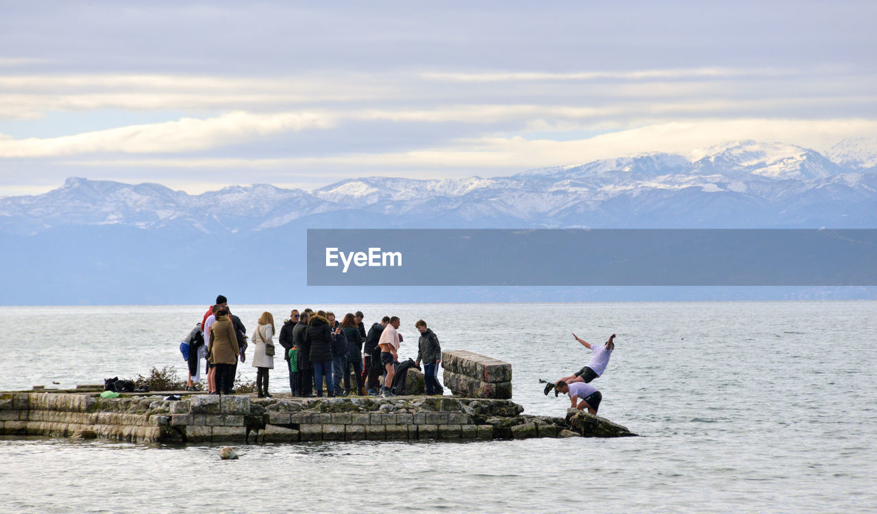 PEOPLE ON SHORE AGAINST SKY