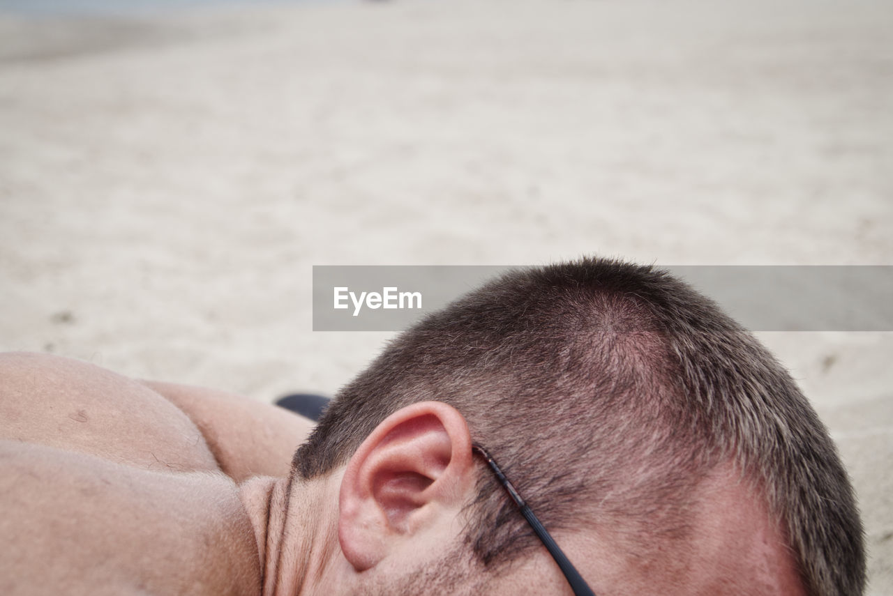 Close-up of man lying at beach