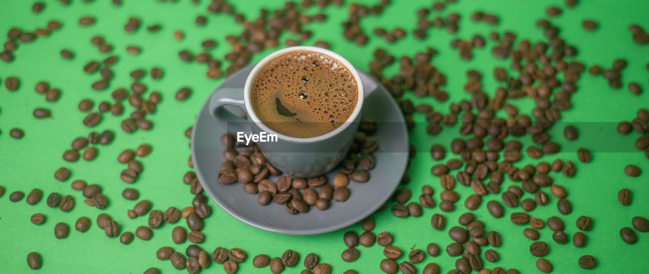 HIGH ANGLE VIEW OF COFFEE CUP ON TABLE AGAINST WALL