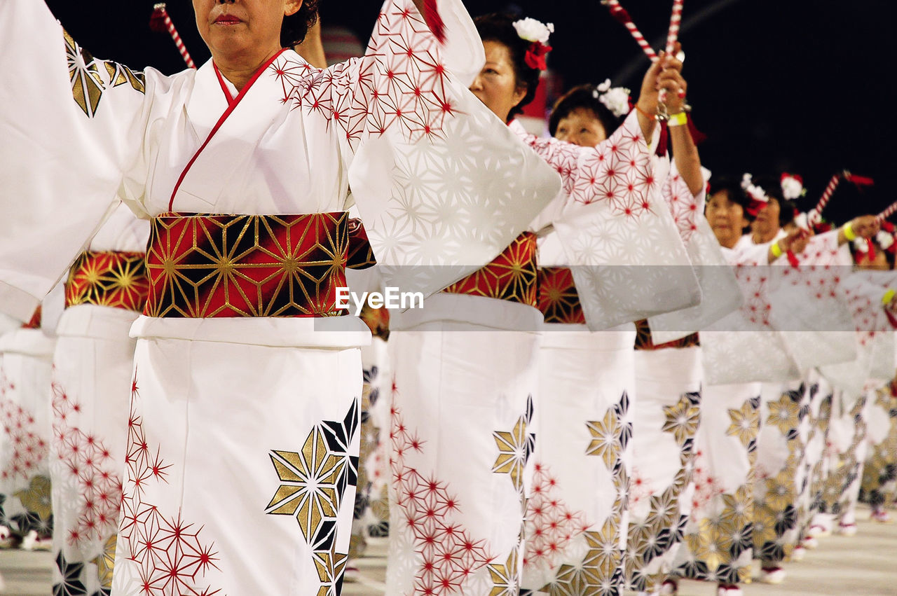 REAR VIEW OF PEOPLE DANCING ON UMBRELLAS