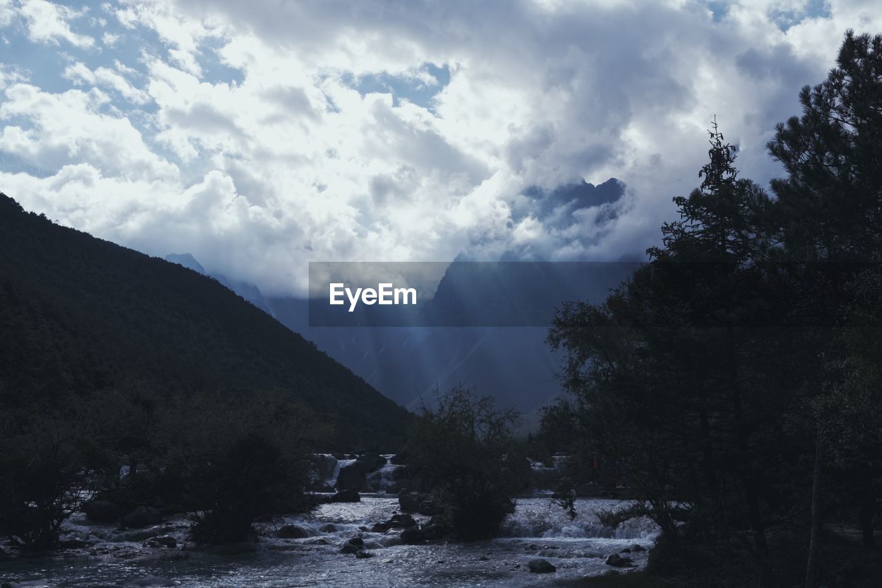 SCENIC VIEW OF WATERFALL BY MOUNTAINS AGAINST SKY