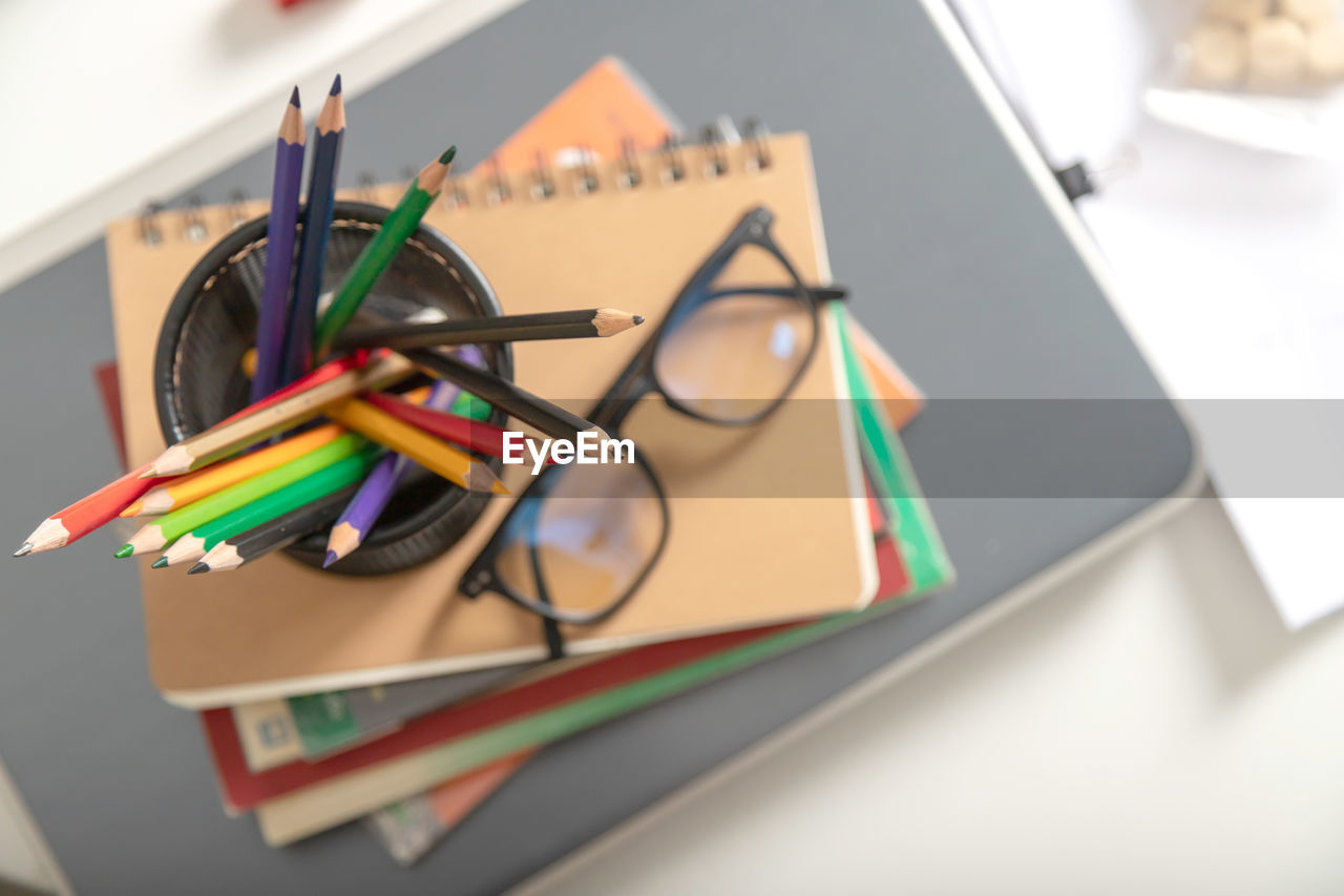 HIGH ANGLE VIEW OF MULTI COLORED PENCILS ON BOOK