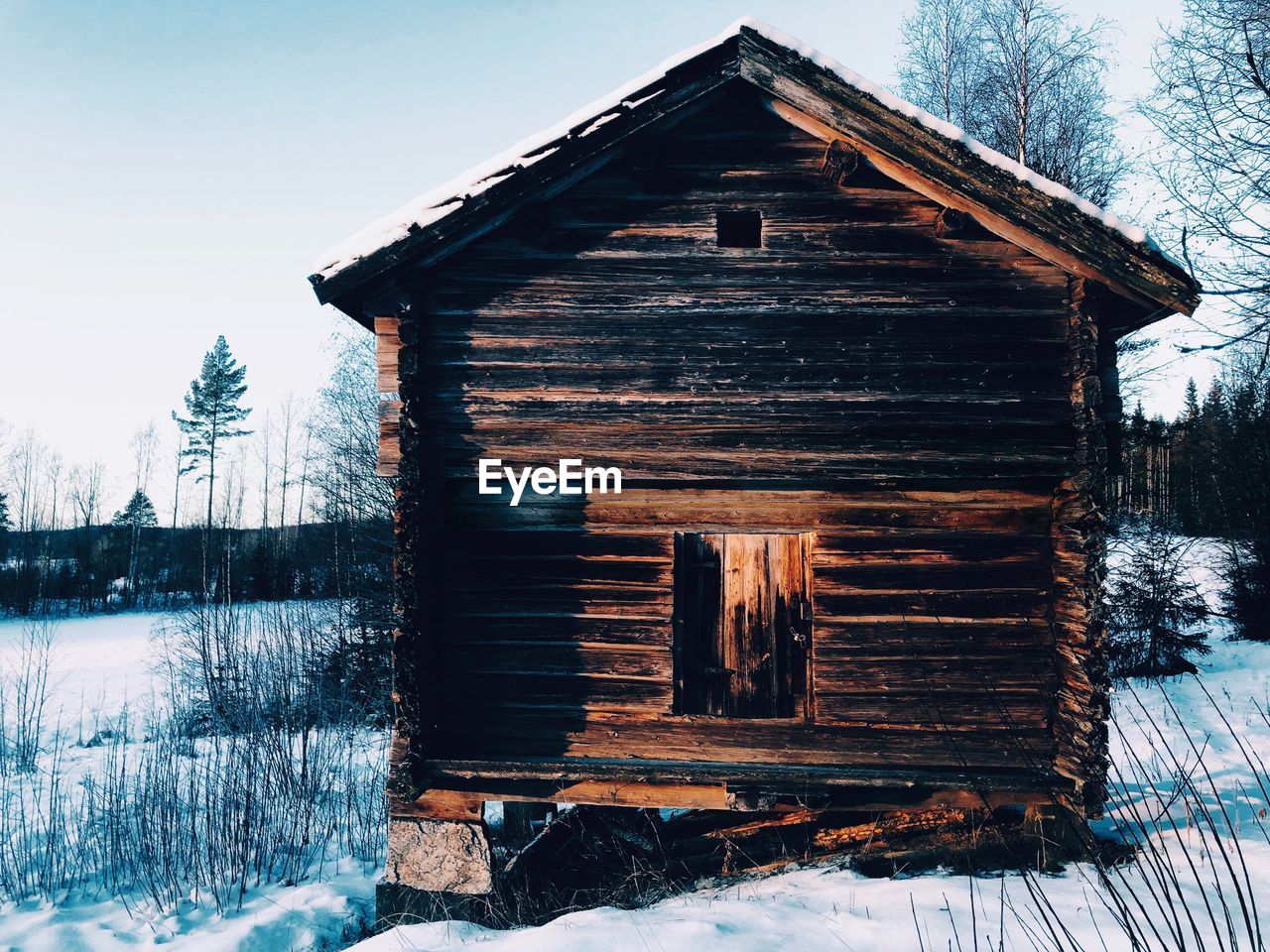 VIEW OF WOODEN HOUSE IN SNOW COVERED FIELD