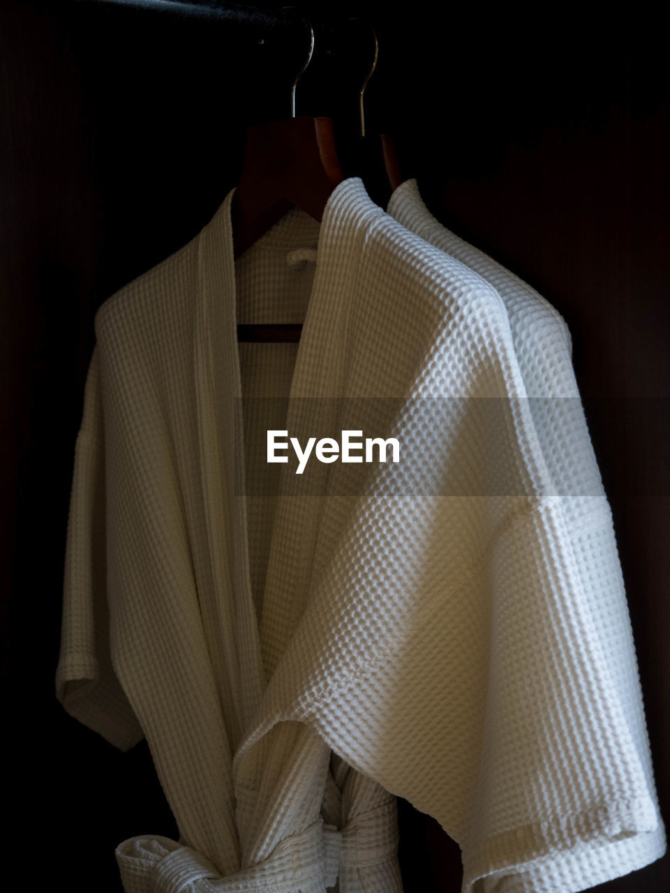 Close-up of bathrobes hanging against black background