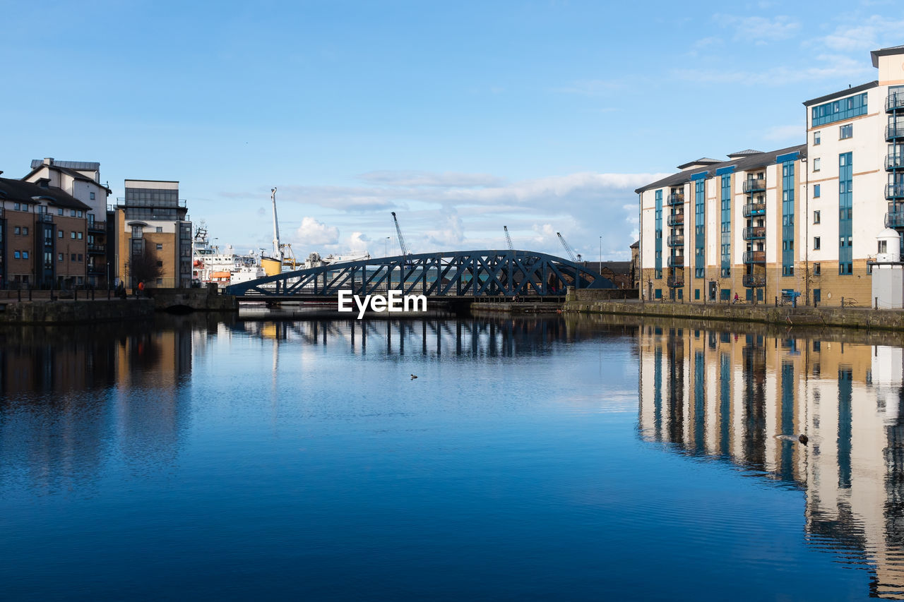 Bridge over river in city against sky