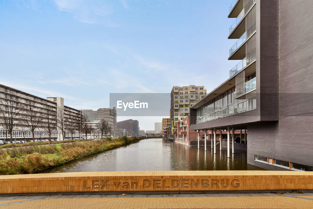 RIVER AMIDST BUILDINGS AGAINST SKY