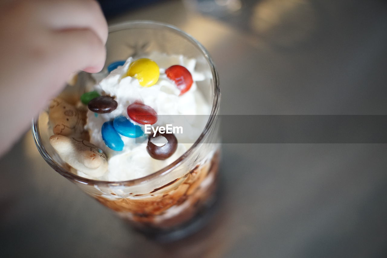 HIGH ANGLE VIEW OF PERSON HOLDING GLASS OF ICE CREAM