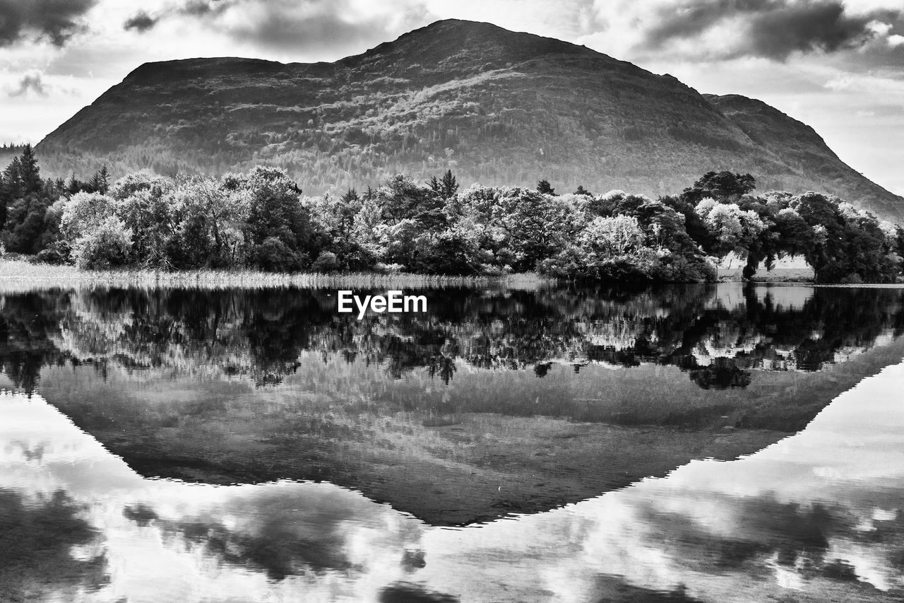 Scenic view of lake and mountains against cloudy sky