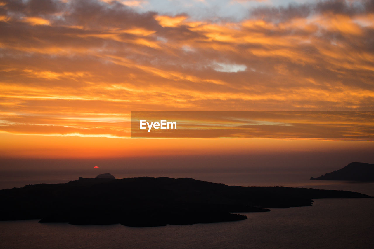 Scenic view of sea against dramatic sky during sunset.  fira, santorini 