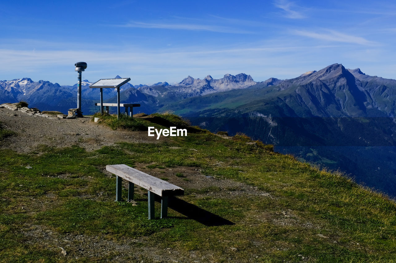 VIEW OF EMPTY BENCH ON MOUNTAIN AGAINST SKY