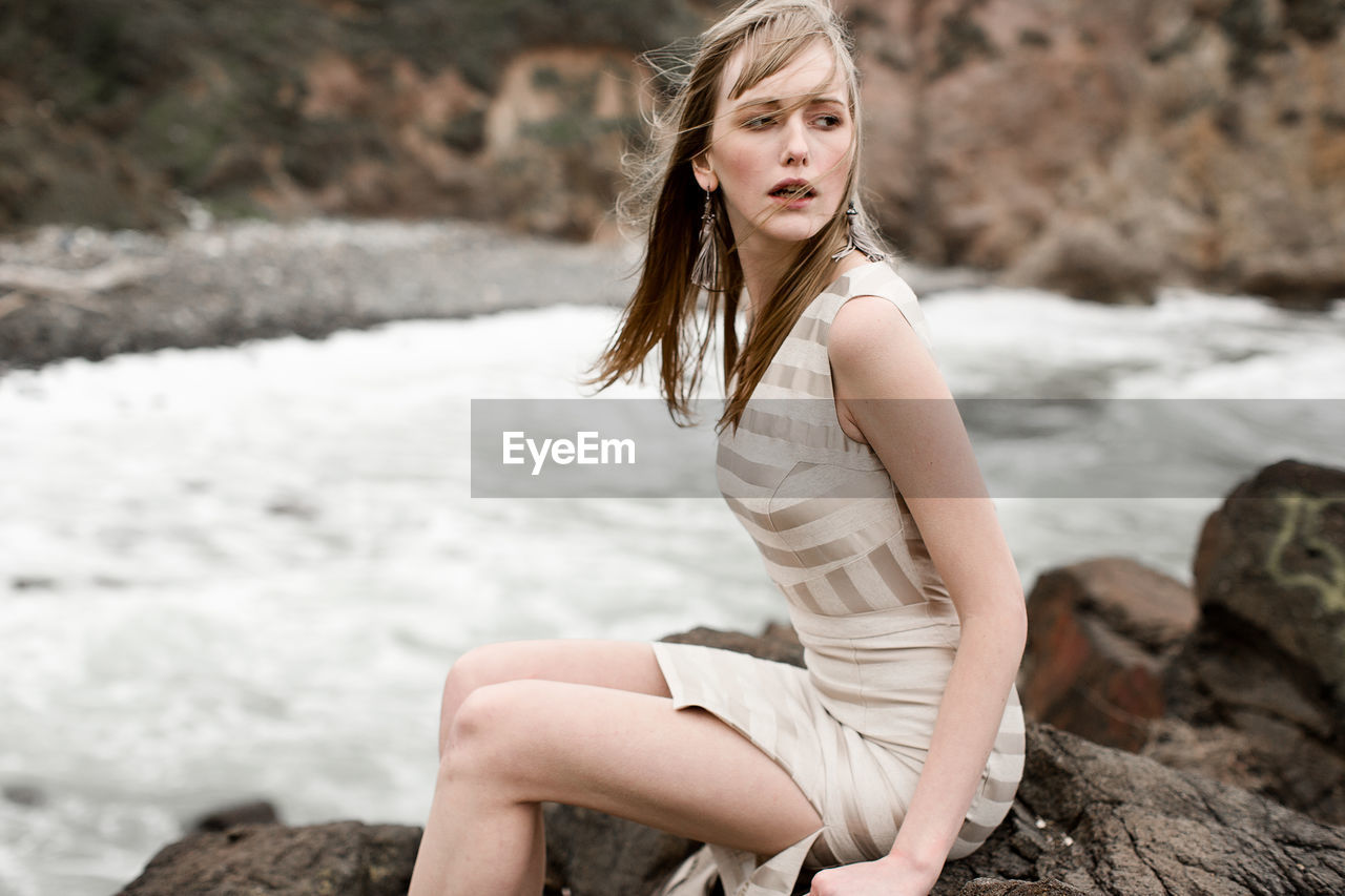 PORTRAIT OF YOUNG WOMAN STANDING ON RAILING