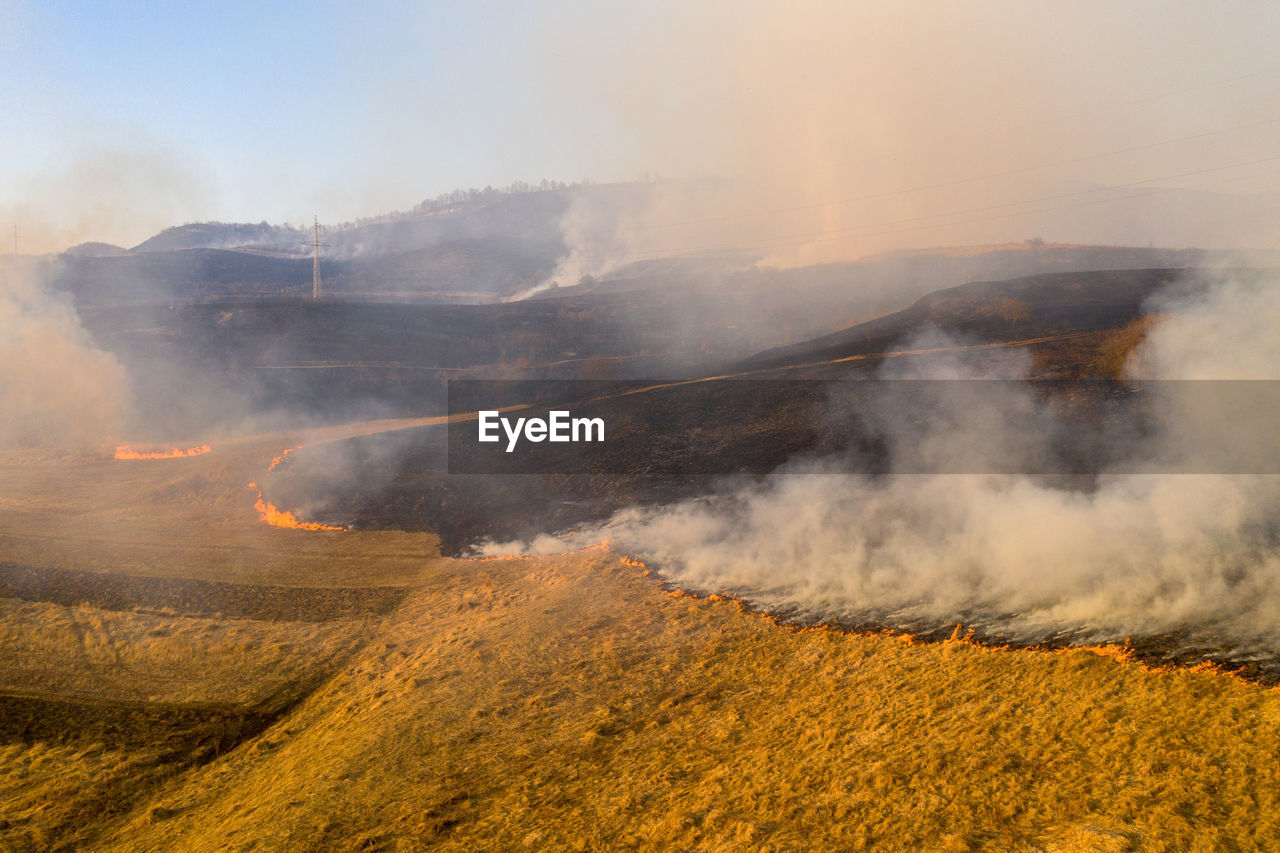 environment, landscape, land, morning, nature, mountain, smoke, beauty in nature, fog, no people, cloud, scenics - nature, field, geology, plant, non-urban scene, heat, outdoors, sky, day, yellow, wildfire, sunlight, burning, travel, social issues, rural scene, accidents and disasters