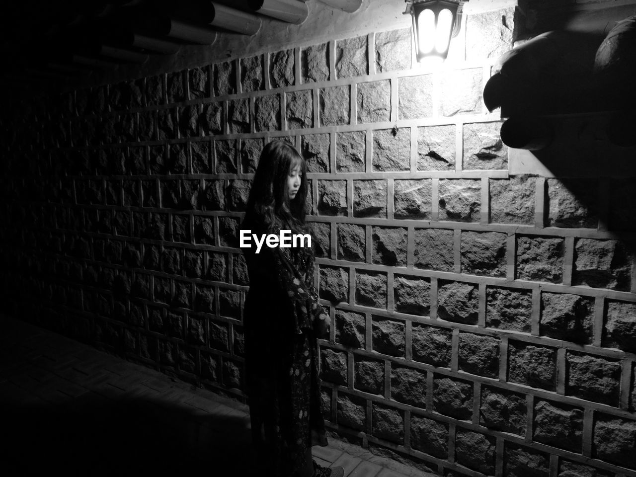 Woman standing by wall at night