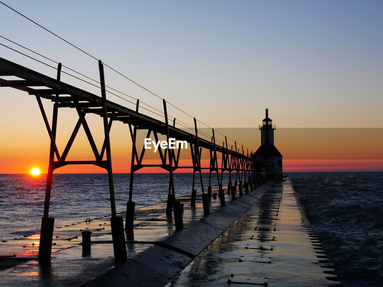 PIER OVER SEA AGAINST ORANGE SKY