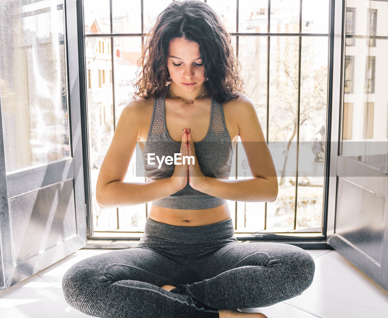 Young girl doing yoga at the window