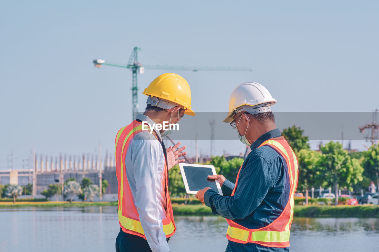 PEOPLE WORKING ON CONSTRUCTION SITE BY CRANE