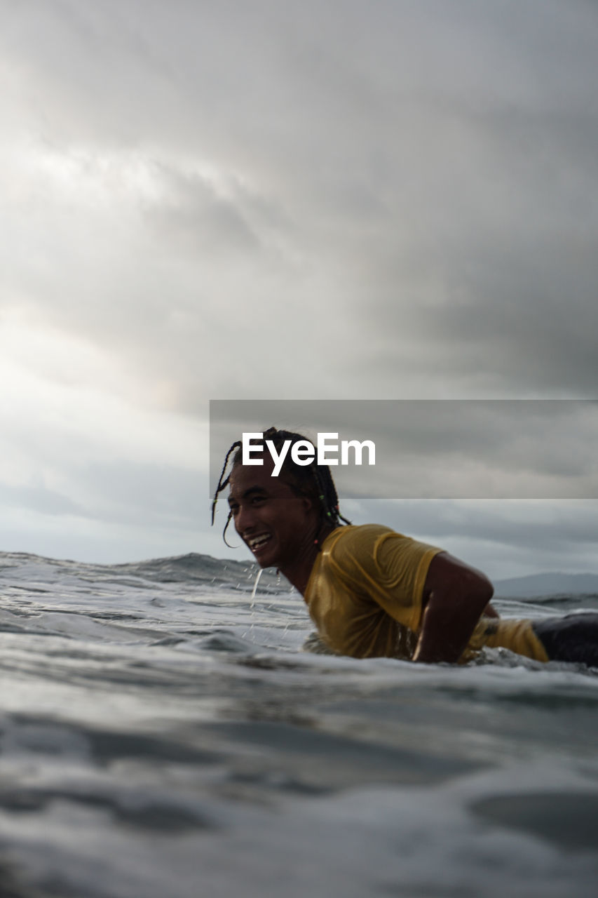 Man surfing in sea against sky