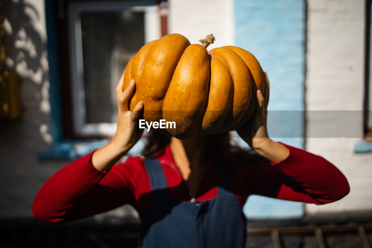 Girl holds big pumpkin on head