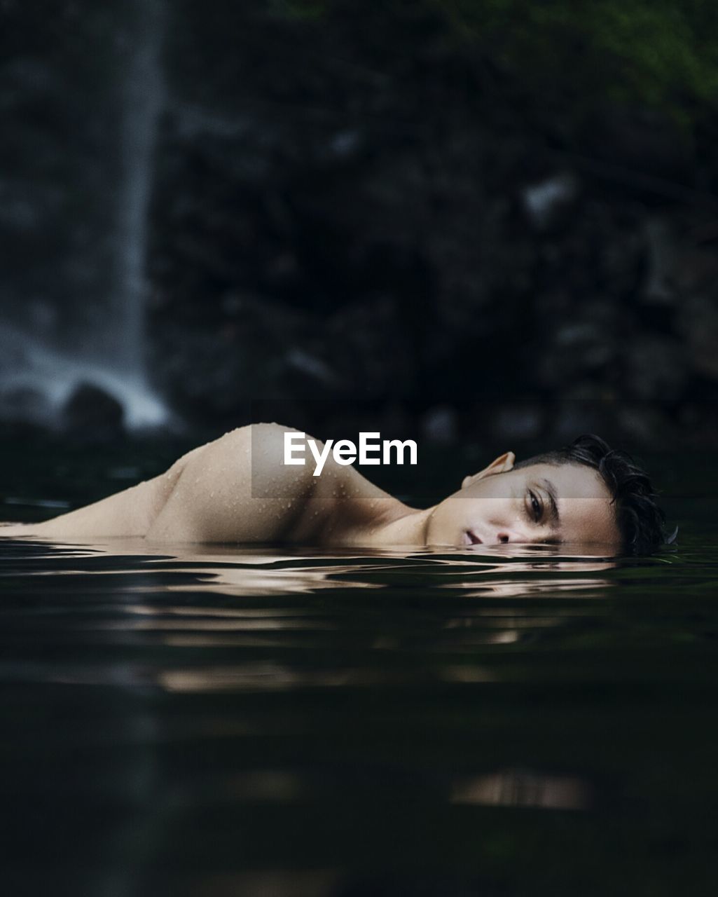 CLOSE-UP OF YOUNG WOMAN SWIMMING UNDERWATER