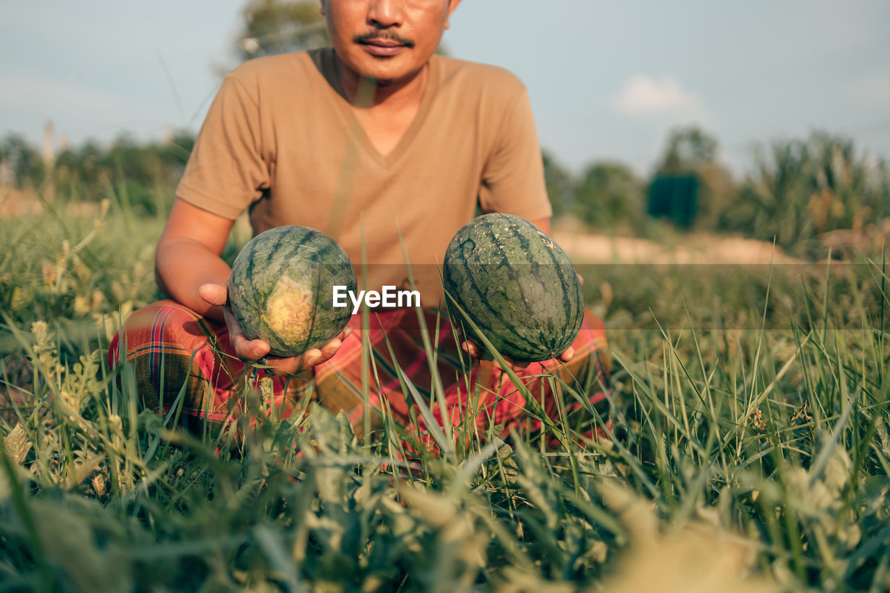 FULL LENGTH OF MAN HOLDING FRESH FIELD IN FARM