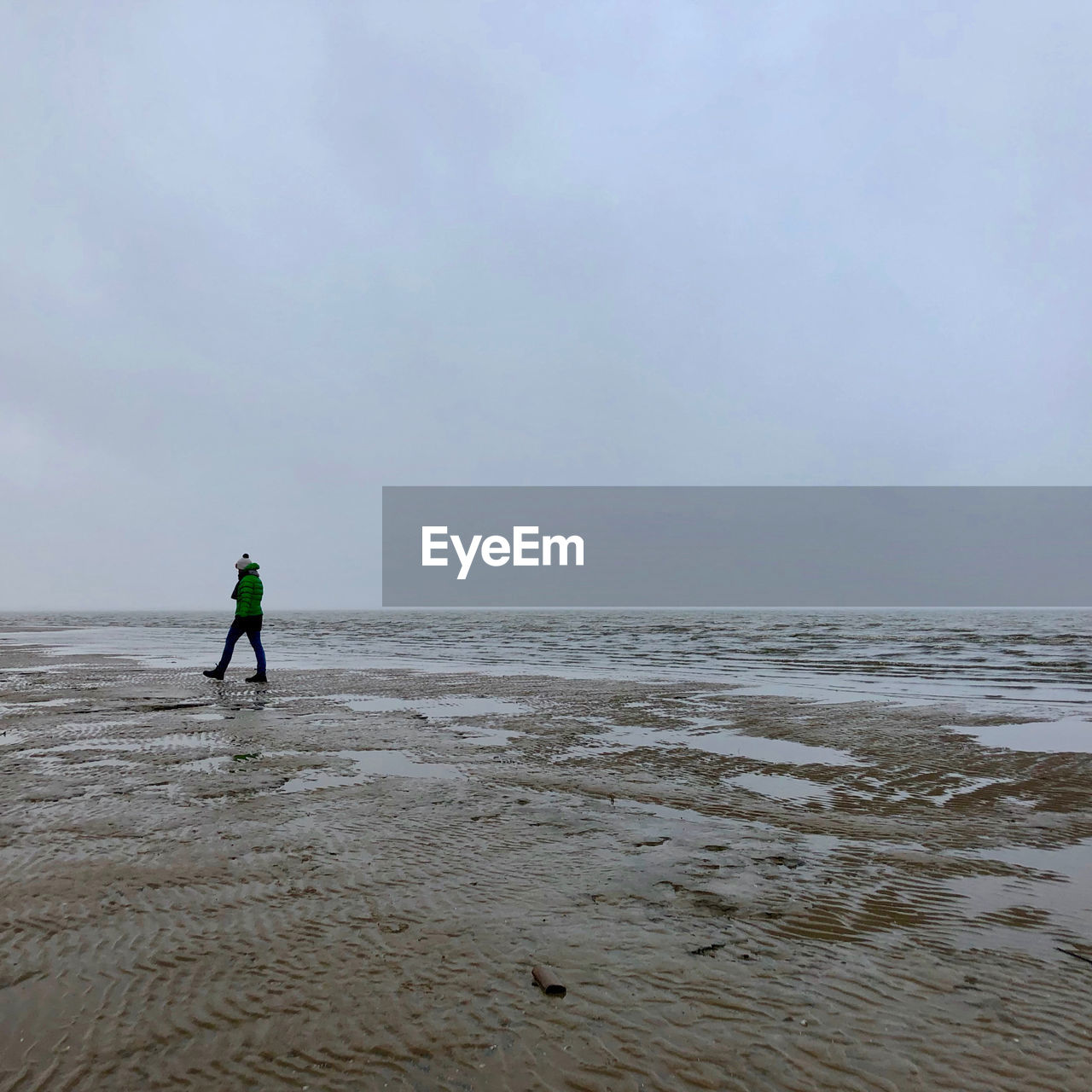 Woman walking at beach against sky