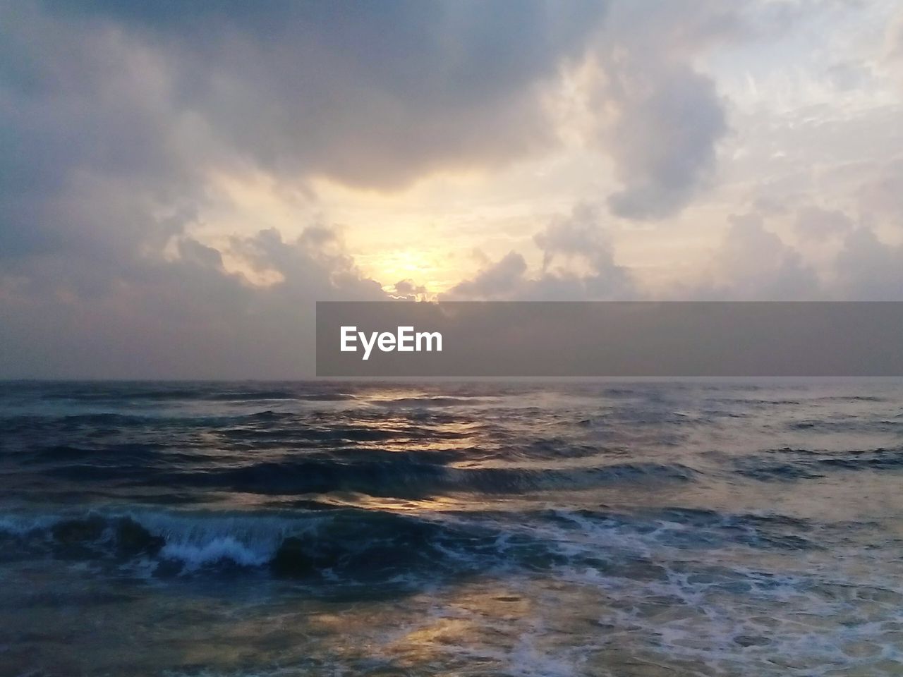 Scenic view of seascape against cloudy sky during sunset