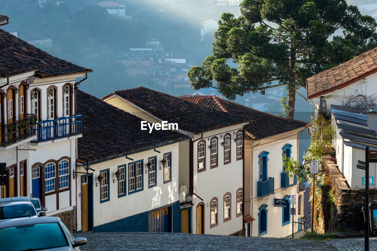 Houses by buildings in city against sky