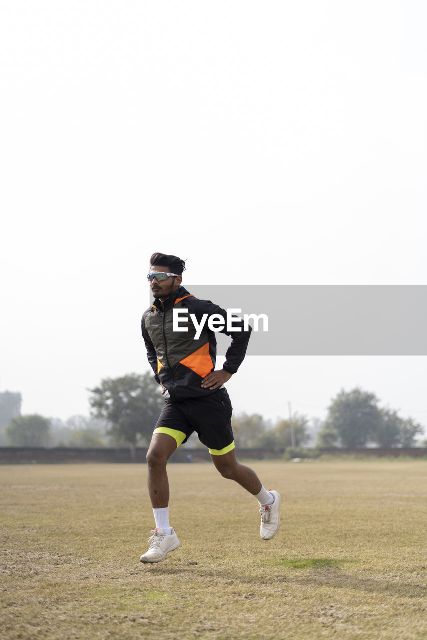 Young indian boy exercising and jumping on the sports field. sports and healthy lifestyle concept.