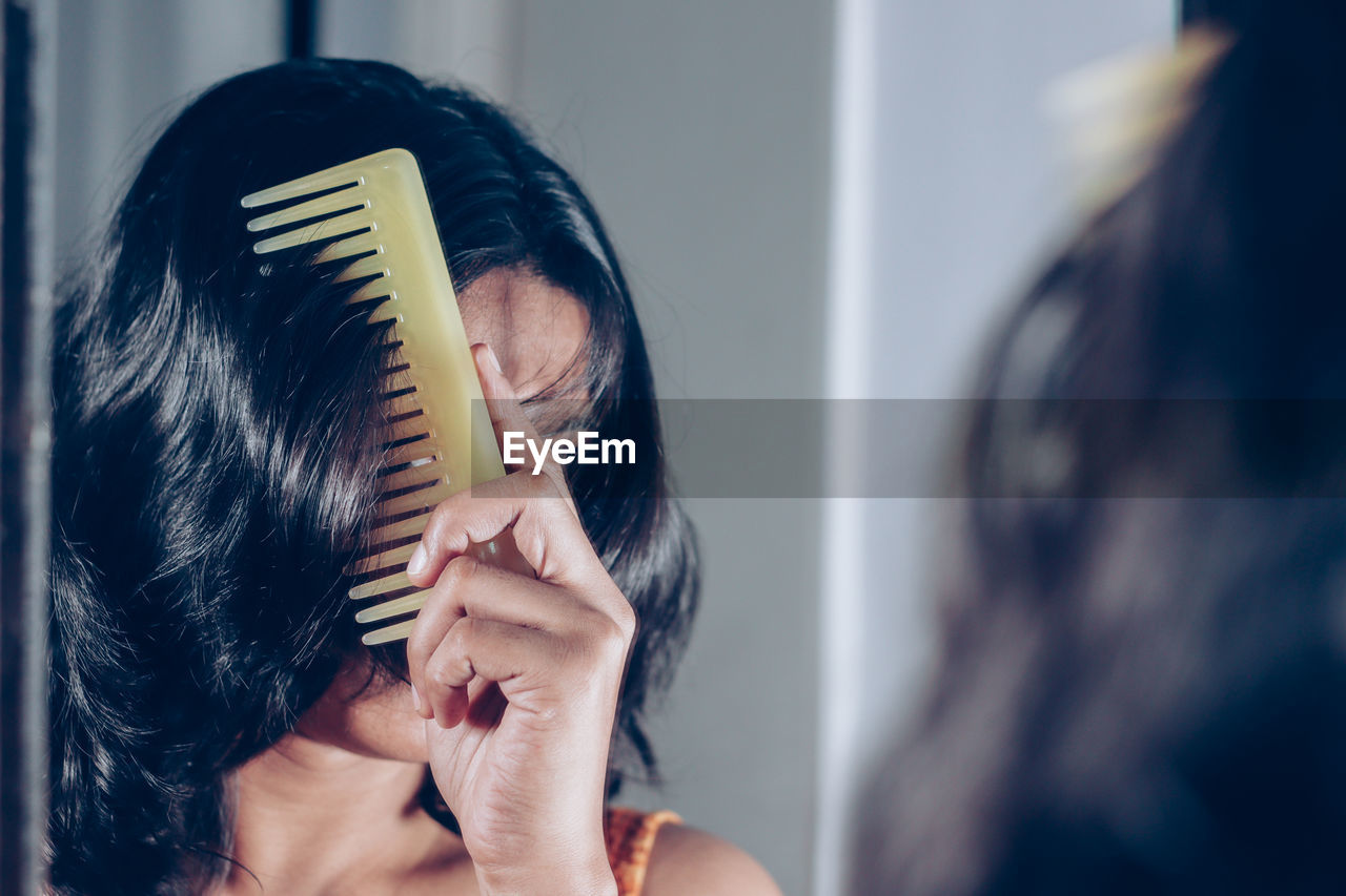 Reflection of woman combing hair on mirror