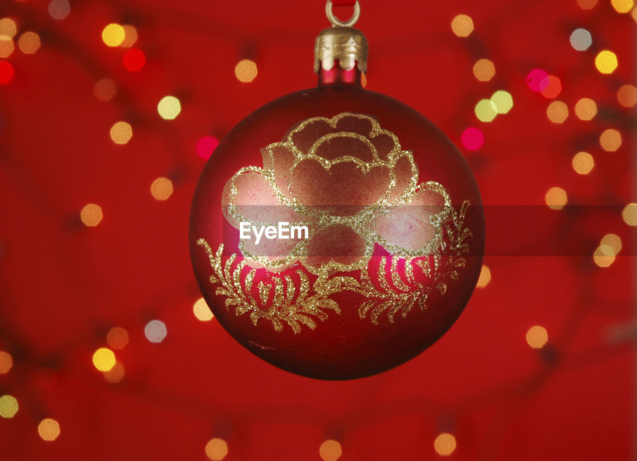 Close-up of red christmas bauble against lights