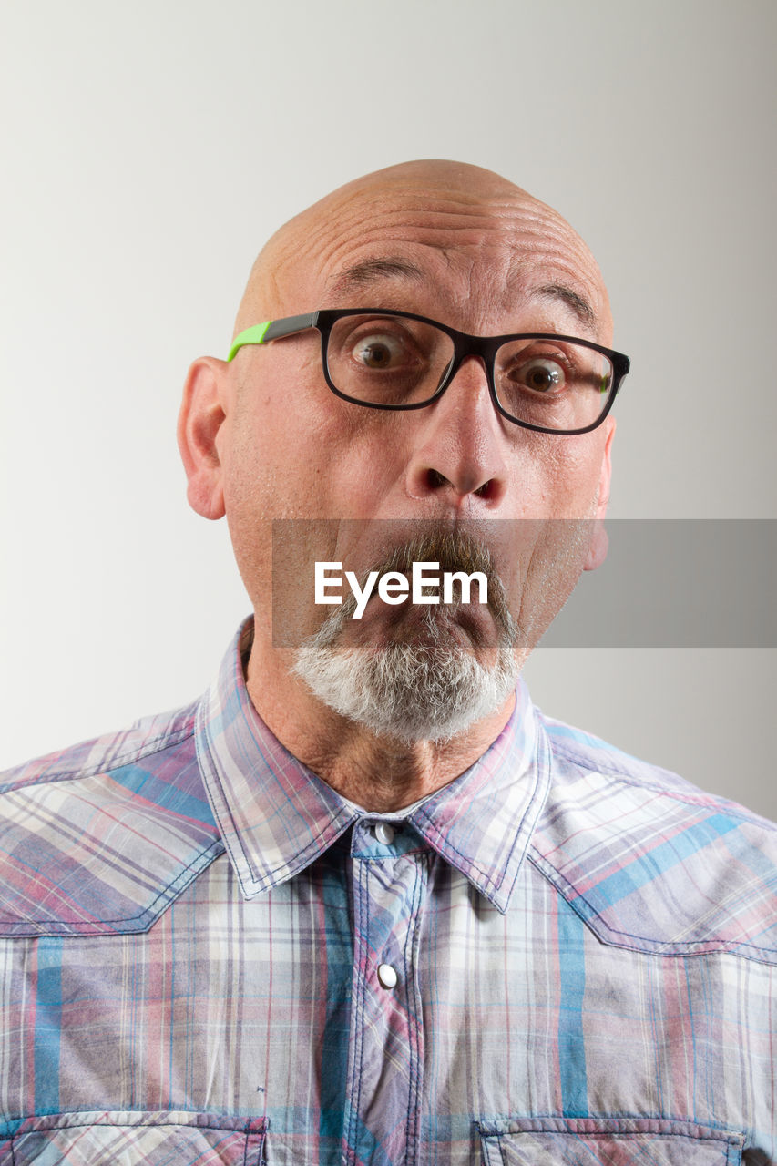 Close-up portrait of man in eyeglasses against gray background