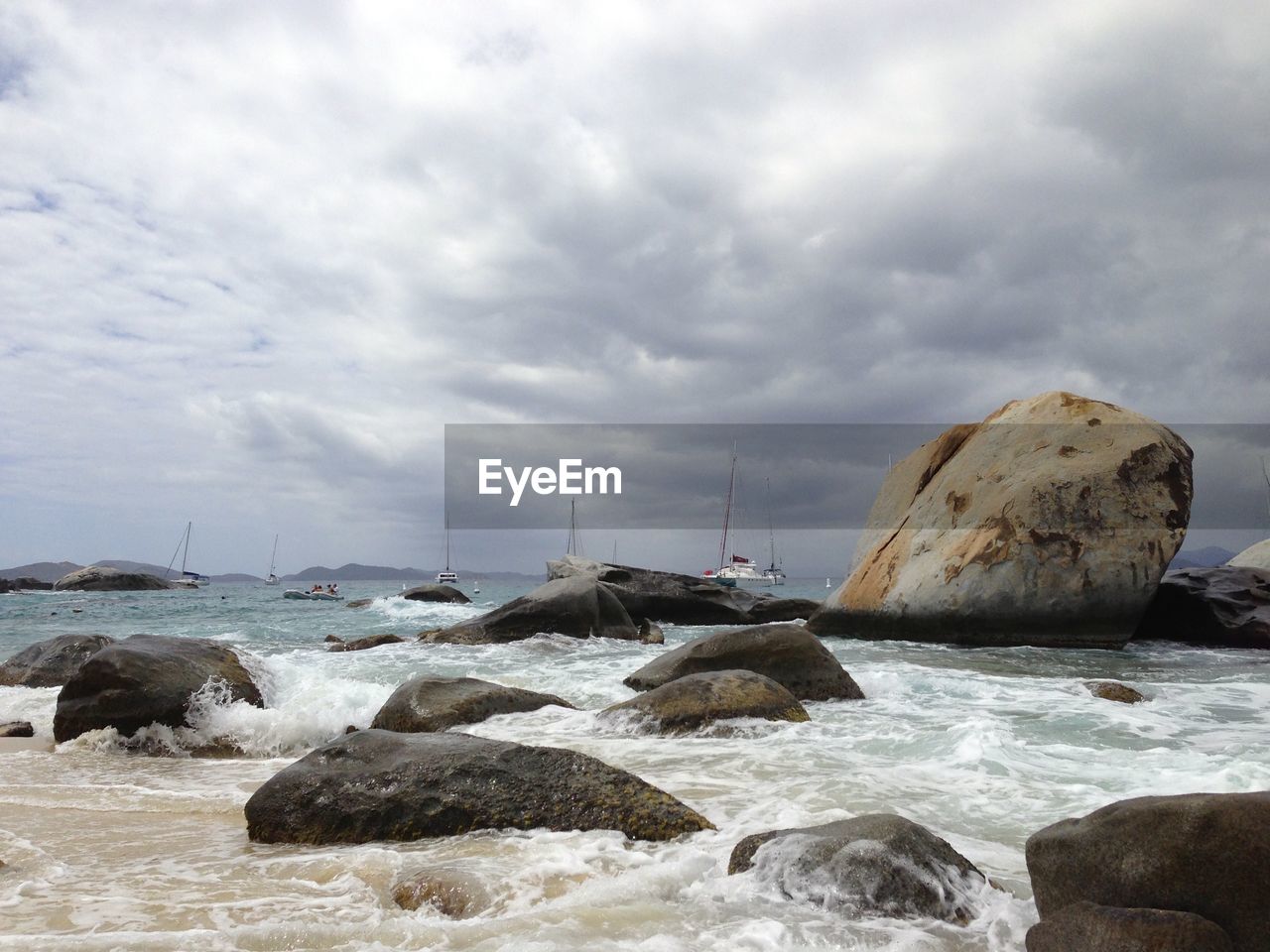 Rocks at beach against cloudy sky