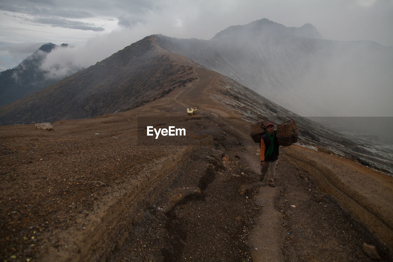 Man carrying sulphur rocks on volcanic mountain