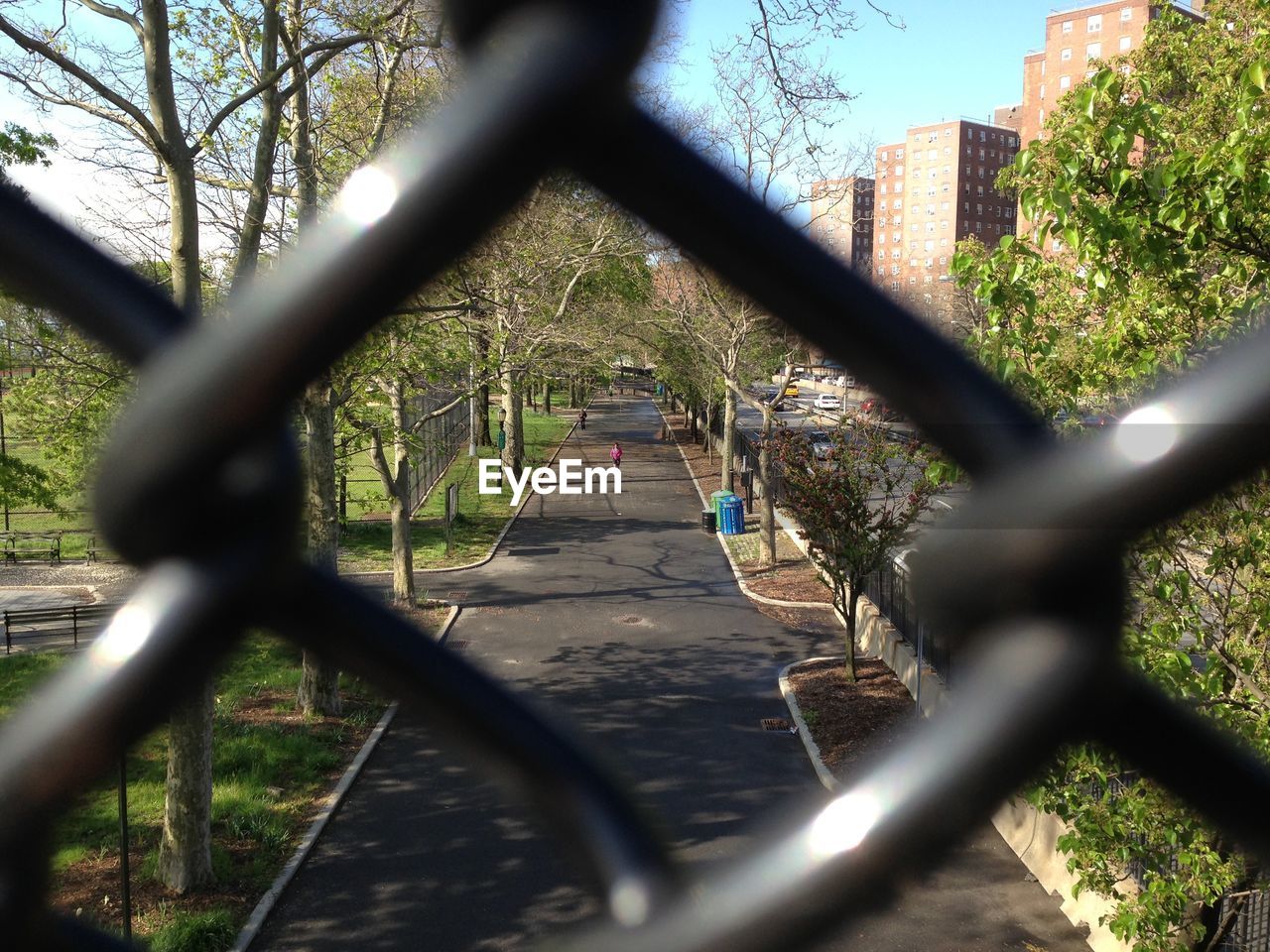 Road by buildings seen through chainlink fence