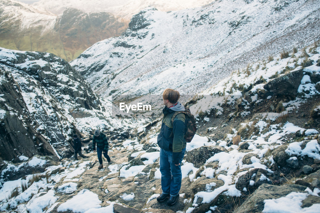 TOURISTS STANDING ON SNOW COVERED MOUNTAIN