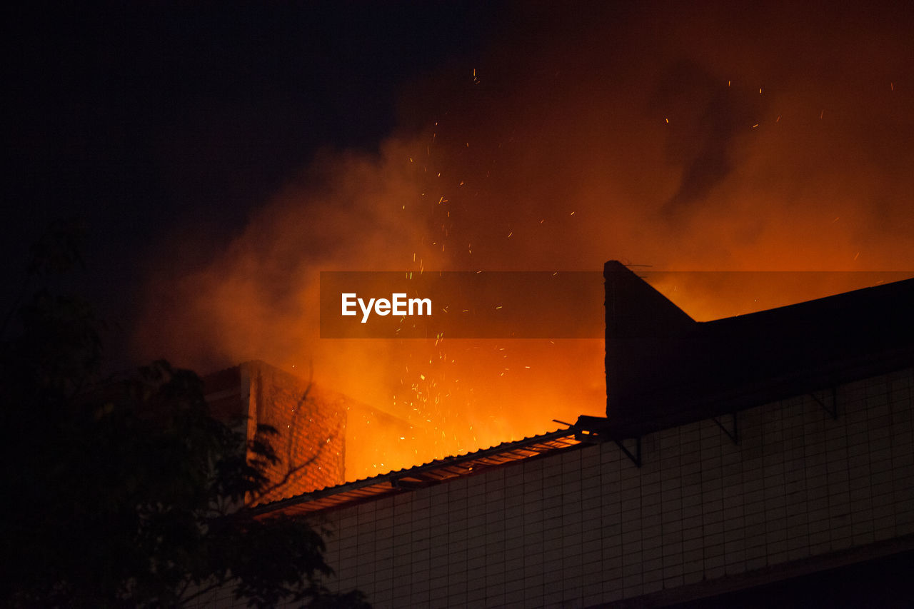 Low angle view of building under fire at night