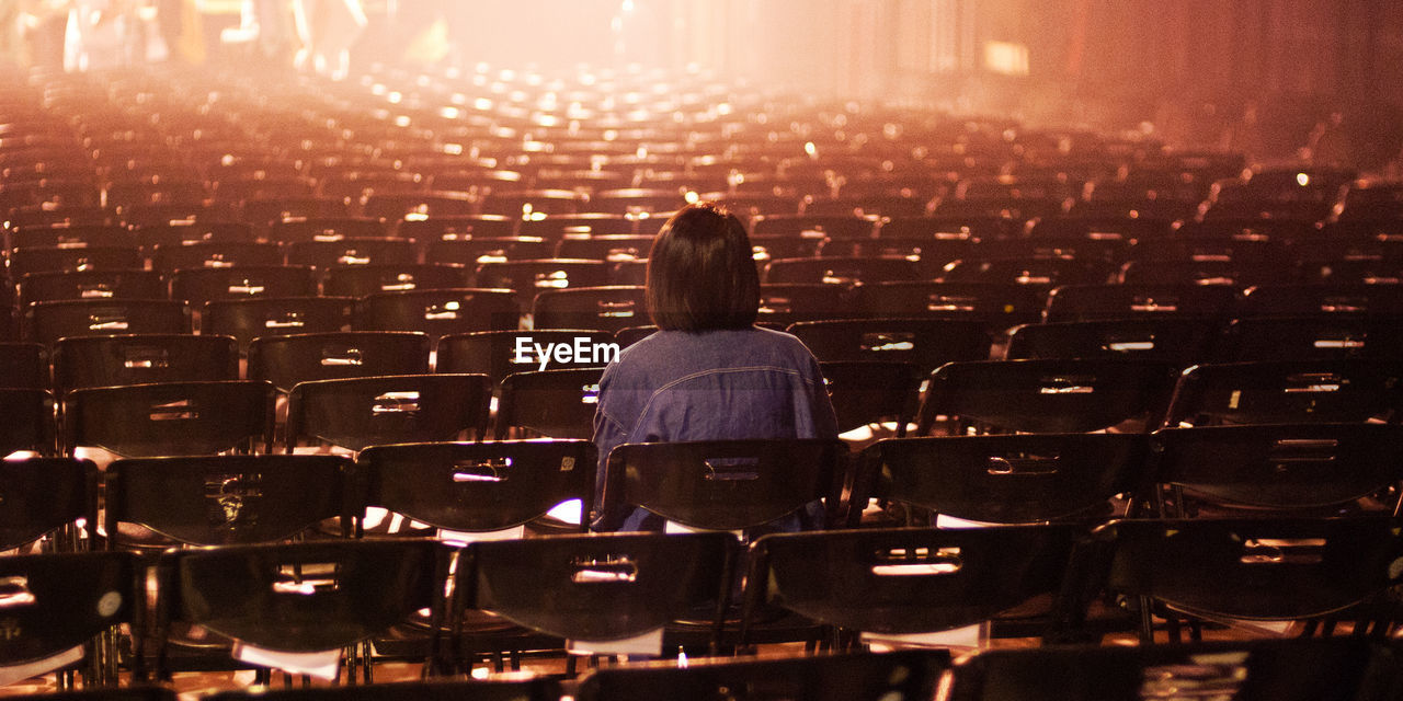 Rear view of woman sitting in empty theater