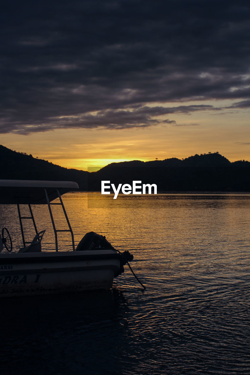 Side view of cropped boat moored in water at dusk