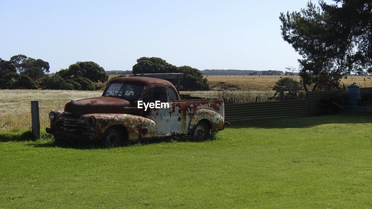 Side view of abandoned car on landscape