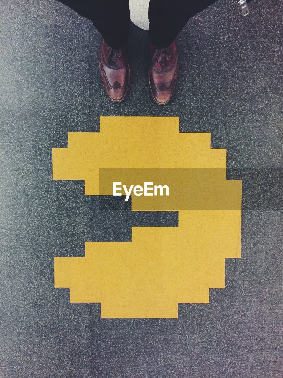 Overhead view of man standing by yellow sign on asphalt