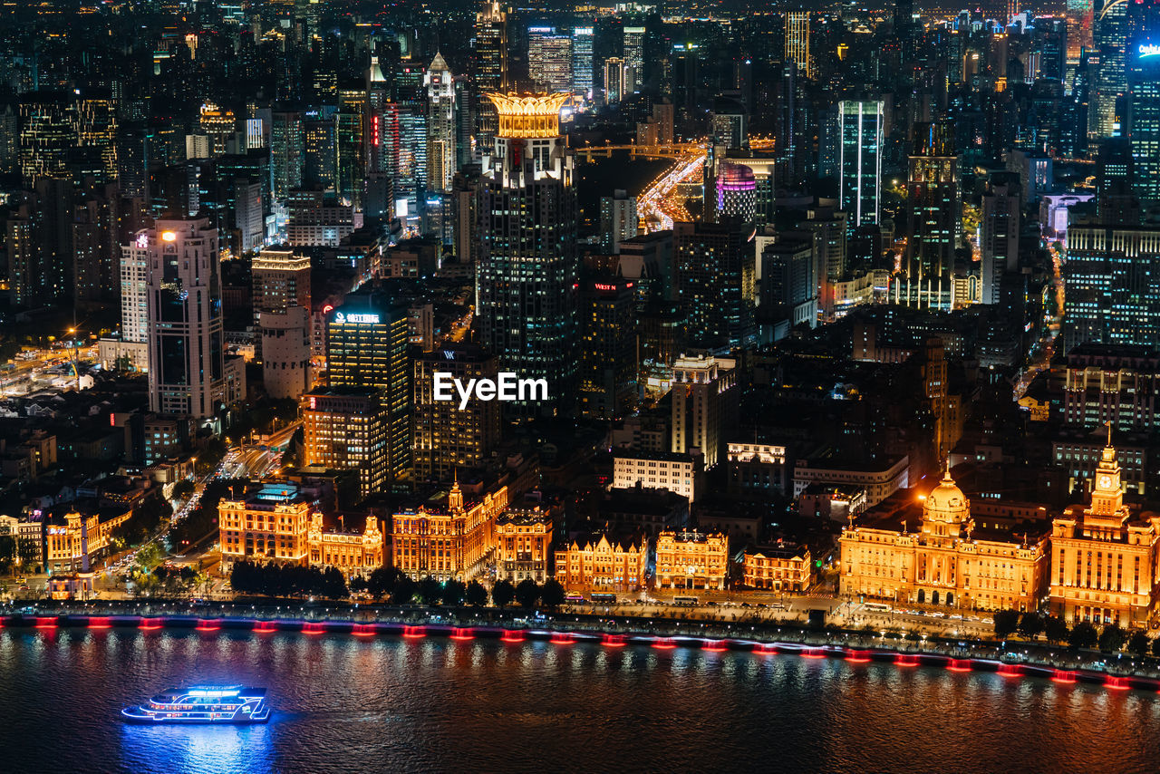 ILLUMINATED MODERN BUILDINGS BY RIVER AT NIGHT