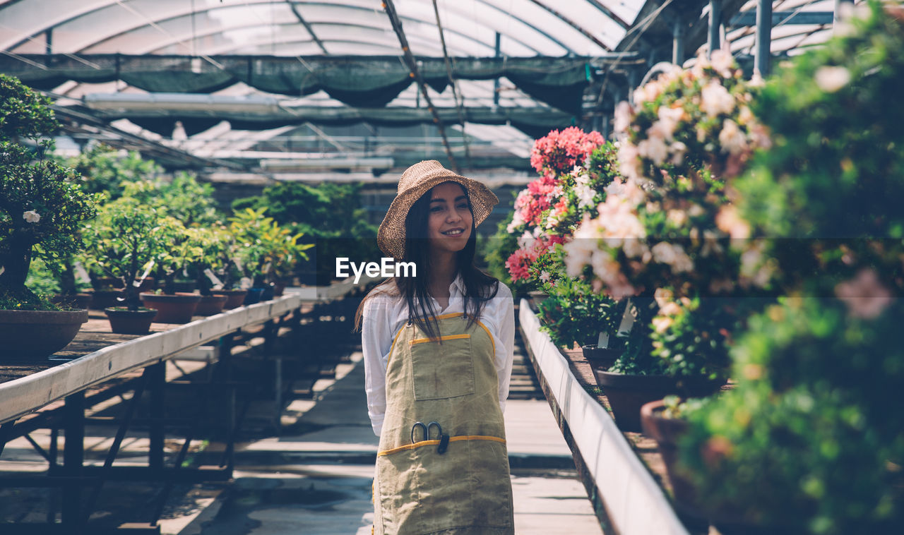 Woman standing by plants in greenhouse