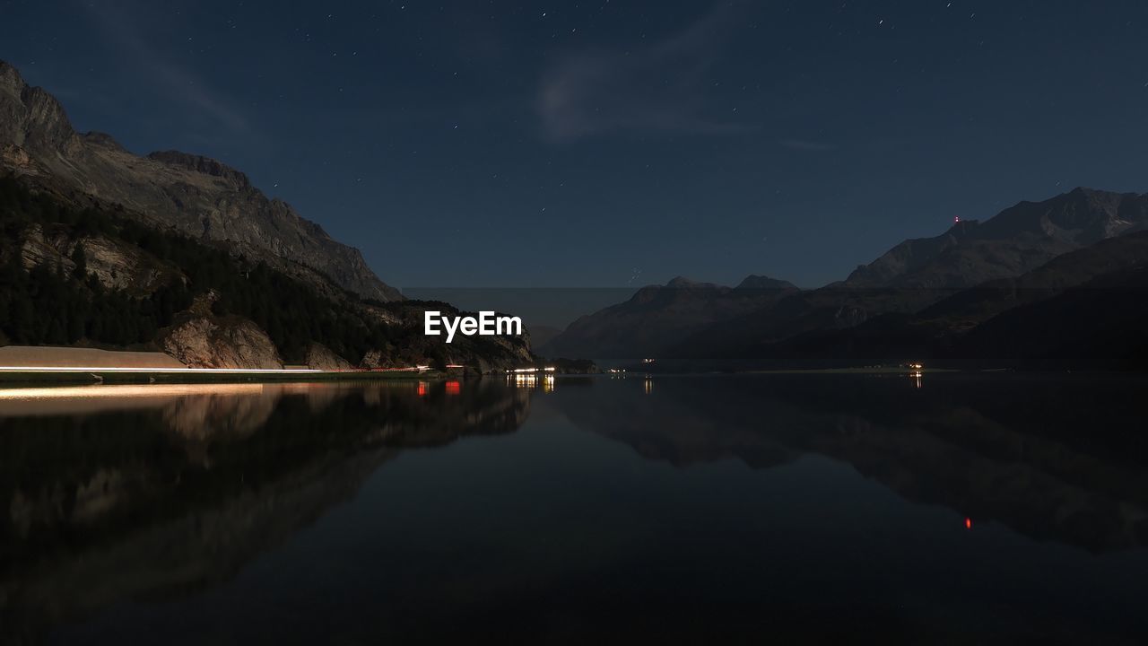 Idyllic shot of mountains against sky with reflection in sea